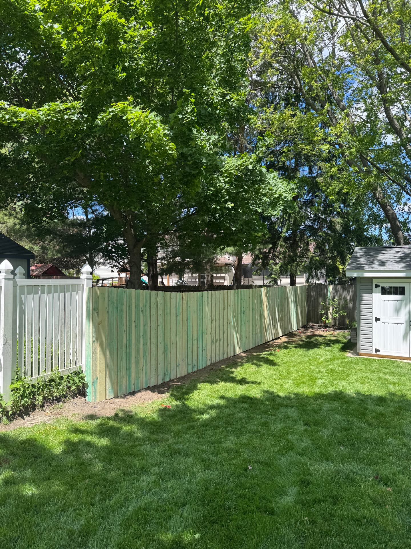 New wood privacy fence installed between a vinyl fence and a backyard shed