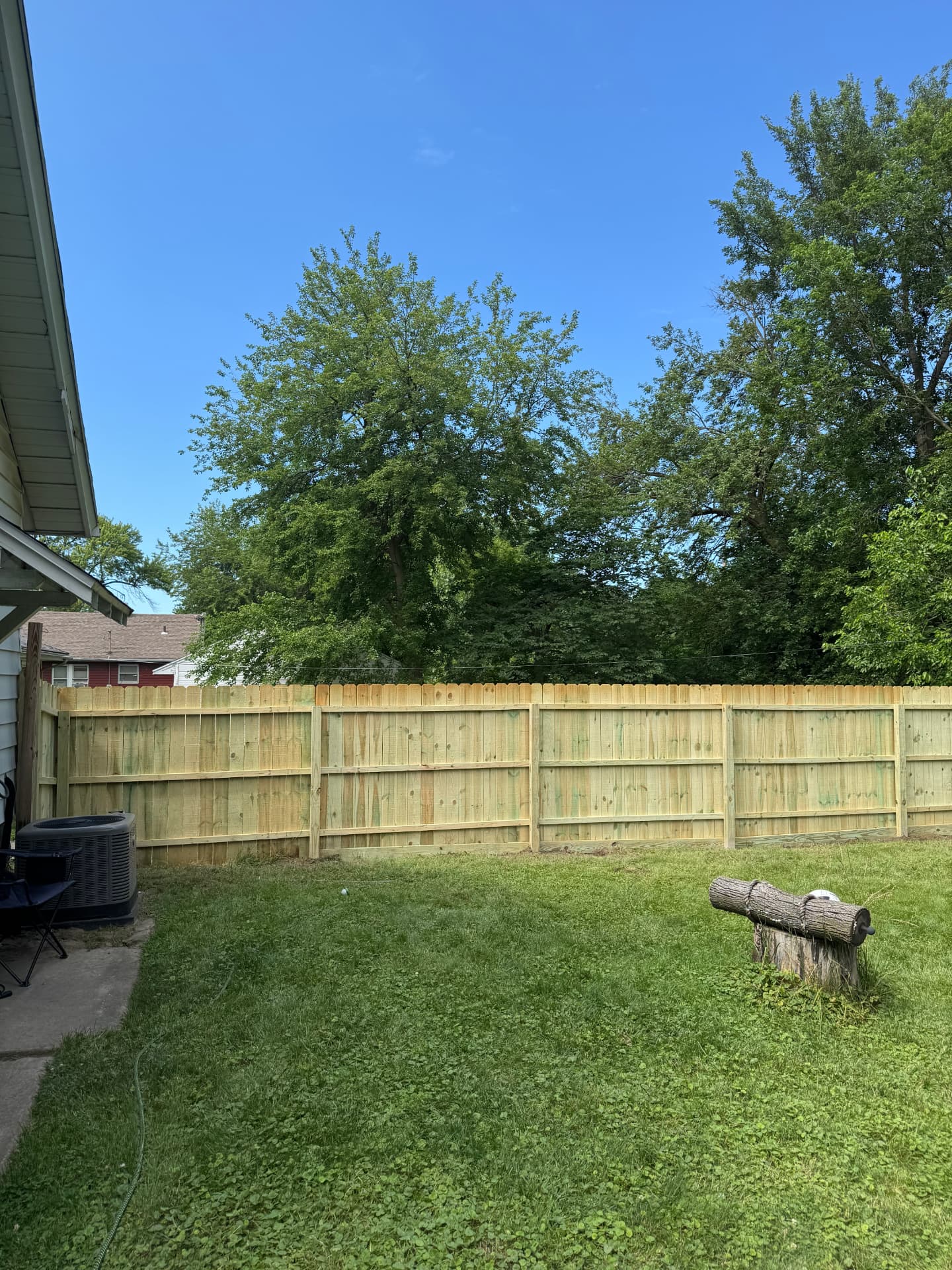 New privacy fence with visible framing along the side of a home next to an AC unit