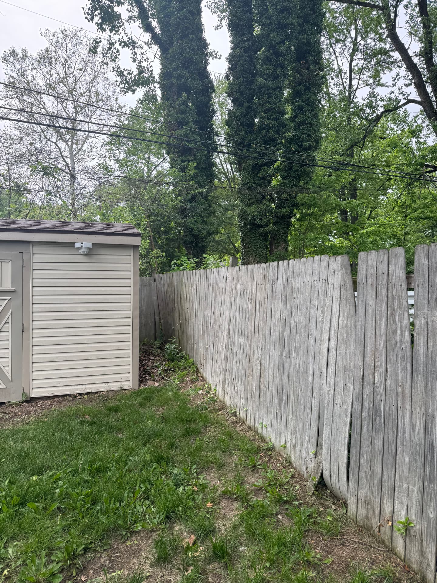 Weathered leaning wood fence in a back yard before HPC repair and replacement