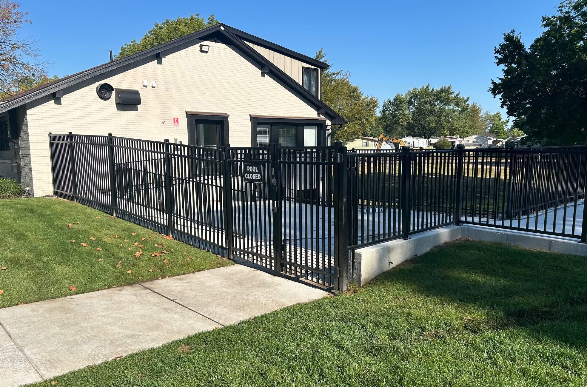 Black aluminum pool fence with self-closing gate at a community clubhouse