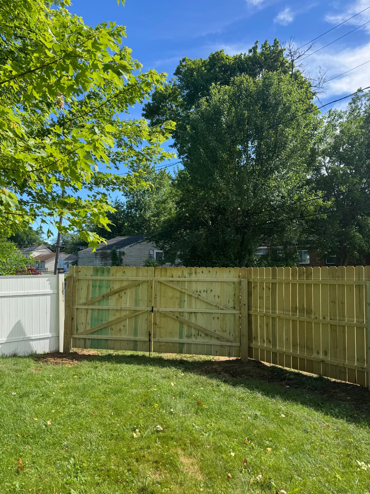 New wood privacy fence and braced double gate next to an existing vinyl fence